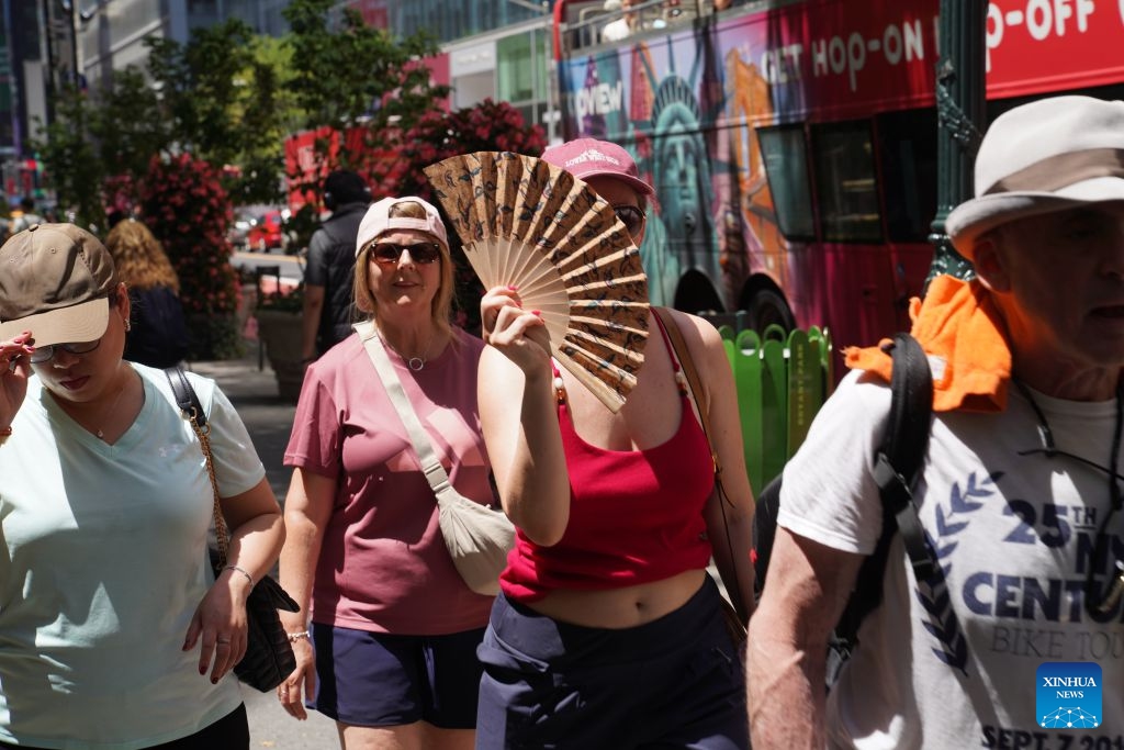 A woman shades herself from the sun with a fan during a heat wave in New York, the United States, on July 2, 2026. (Xinhua/Zhang Fengguo)