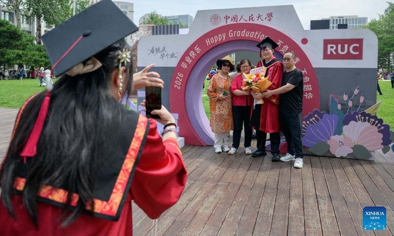 A student poses for photos with his relatives after the graduation ceremony at Renmin University of China in Beijing, capital of China, July 4, 2026. Renmin University of China held the graduation ceremony on Saturday and saw about 8,244 graduates participating in the on-campus celebrations. (Photo: Xinhua)