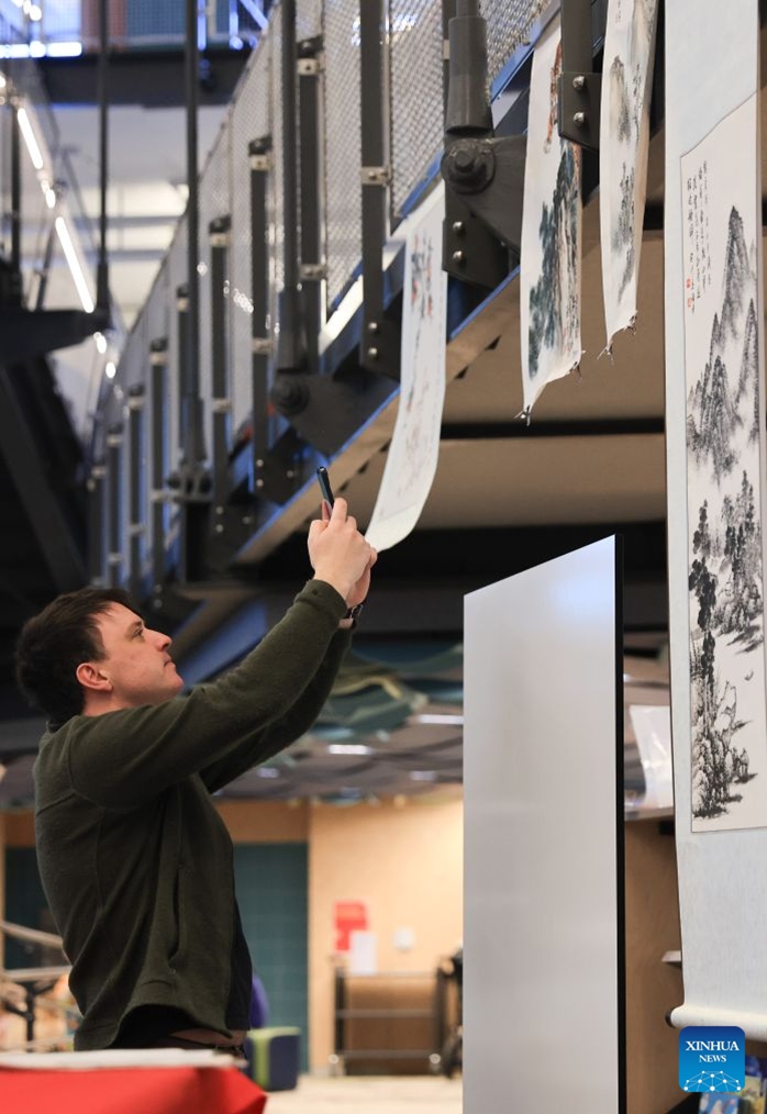 A man takes photos of traditional Chinese paintings during a Chinese Language Week event in Wellington, New Zealand on July 4, 2026. (Photo by Meng Tao/Xinhua)


