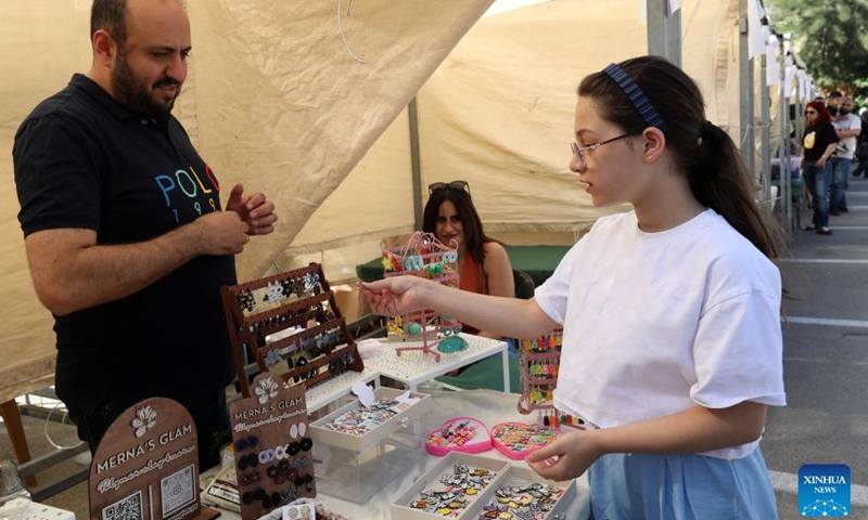 A woman selects products at the Harjeh Market in the West Bank city of Ramallah, July 3, 2026. The market is a vibrant cultural event that brings together a diverse selection of traditional handicrafts, handmade products, and local foods, offering visitors an opportunity to experience the richness and diversity of Palestinian heritage. It is held every Friday in Ramallah's Old Town from late June through early August. (Photo by Ayman Nobani/Xinhua)