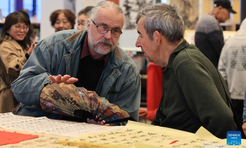 People discuss over a painting work during a Chinese Language Week event in Wellington, New Zealand on July 4, 2026. (Photo by Meng Tao/Xinhua)


