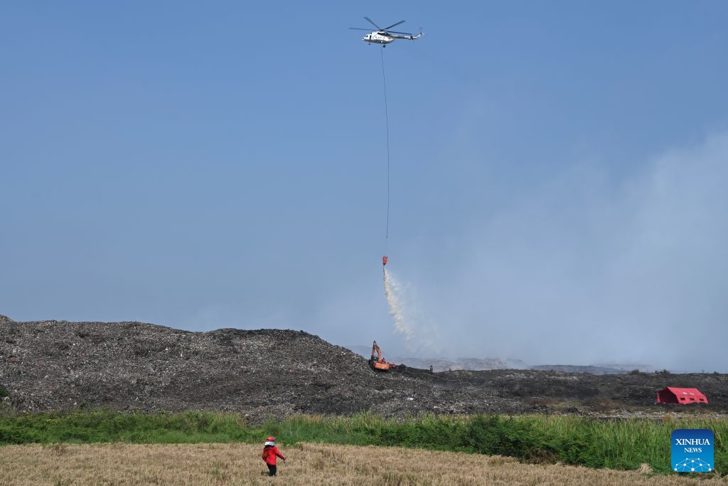 A helicopter with water bombing attempts to put out a fire at a smoldering landfill in Tangerang Regency of Banten Province, Indonesia on July 5, 2026. The Indonesian government has warned all local governments to step up preparedness for potential fires at landfills amid forecasts of extreme weather conditions over the coming months, local media reported on Saturday. This follows a blaze at a landfill in Tangerang regency, near the Indonesian capital city of Jakarta, which has remained unextinguished for days. (Xinhua/Veri Sanovri)