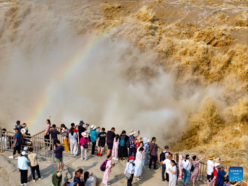 An aerial drone photo taken on July 6, 2026 shows people visiting the Hukou Waterfall on the Yellow River in Jixian County, north China's Shanxi Province. The waterfall is witnessing an increasing water flow lately. (Photo: Xinhua)