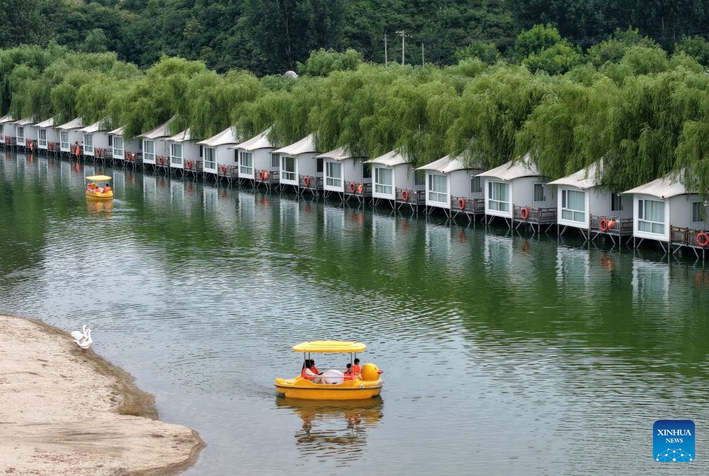 A drone photo shows tourists taking boats at a camping site in Lingshou County of north China's Hebei Province, July 4, 2026. Shijiazhuang has developed a camping-based tourism brand to enrich short-getaway options for tourists, boost consumption and promote rural revitalization. (Photo: Xinhua)