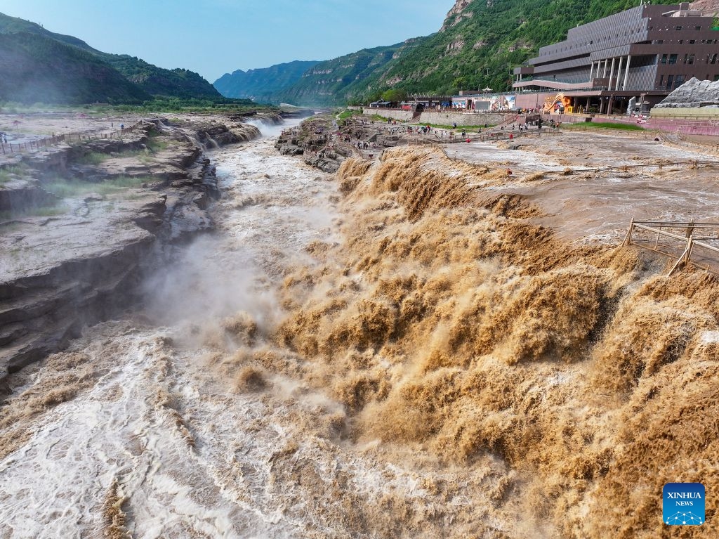 An aerial drone photo taken on July 6, 2026 shows people visiting the Hukou Waterfall on the Yellow River in Jixian County, north China's Shanxi Province. The waterfall is witnessing an increasing water flow lately. (Photo: Xinhua)