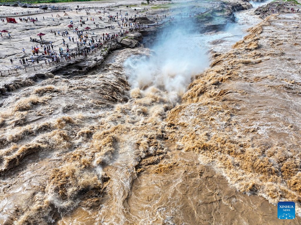 An aerial drone photo taken on July 6, 2026 shows people visiting the Hukou Waterfall on the Yellow River in Jixian County, north China's Shanxi Province. The waterfall is witnessing an increasing water flow lately. (Photo: Xinhua)
