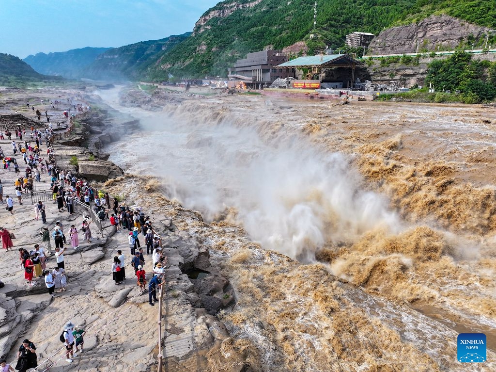 An aerial drone photo taken on July 6, 2026 shows people visiting the Hukou Waterfall on the Yellow River in Jixian County, north China's Shanxi Province. The waterfall is witnessing an increasing water flow lately. (Photo: Xinhua)