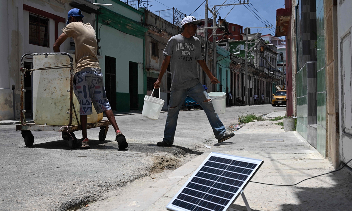 Men carry water near a solar panel in Havana, Cuba, on July 6, 2026, during a nationwide power outage. Cuba's state-run National Electric Union said Monday that the country's national power system suffered a total outage. The union wrote on X that the cause was under investigation and that it would continue to provide updates, Xinhua reported. Photo: VCG