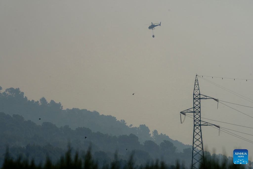A helicopter carries water to put out a wildfire in Sentmenat, Barcelona, Spain, on July 7, 2026. According to satellite-based estimates from the European Forest Fire Information System (EFFIS), wildfires have burned around 56,000 hectares in Spain so far this year. (Photo: Xinhua)