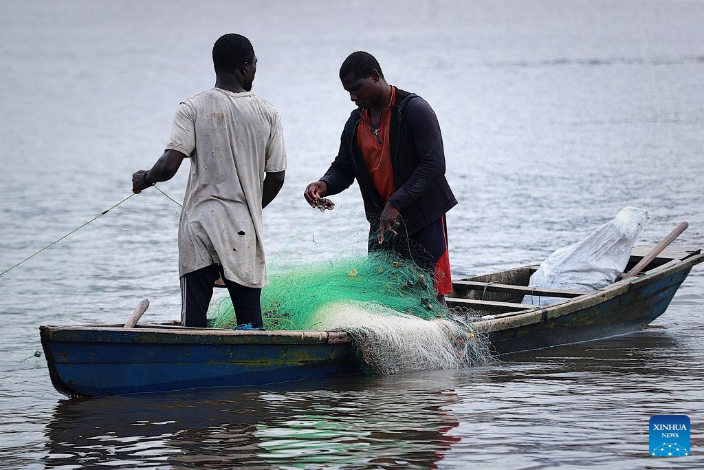 Two local fishermen catch fish on the Ebrie Lagoon in Abidjan, Cote d'Ivoire, on July 6, 2026. The Ebrie Lagoon, covering an area of about 560 square kilometers in southern Cote d'Ivoire, is one of the most important coastal lagoon systems in West Africa. The country's economic capital, Abidjan, stretches along both shores of the Ebrie Lagoon. The lagoon not only supports port operations, waterborne transportation and fisheries, but also weaves itself into local residents' daily lives, forging the city's distinctive character. (Photo: Xinhua)