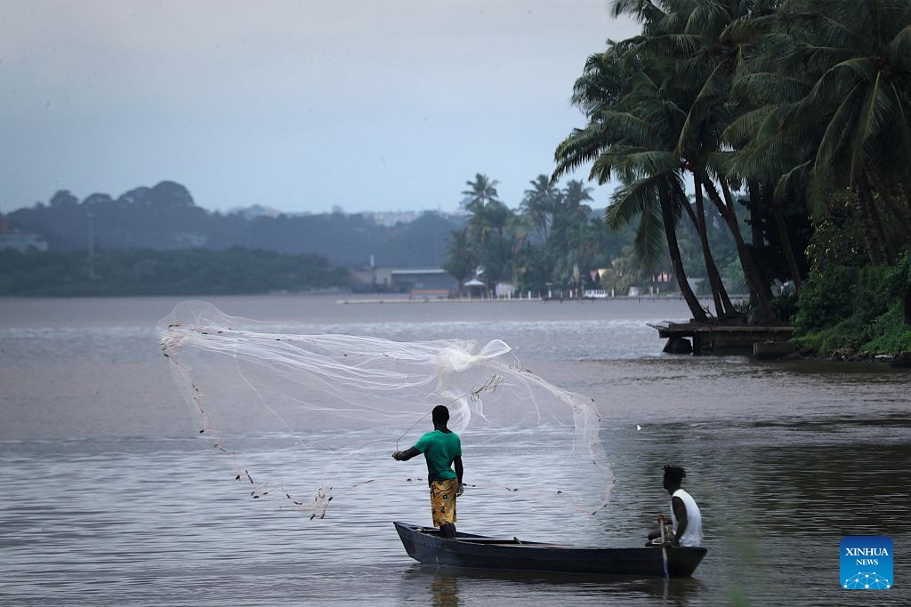 Two local fishermen catch fish on the Ebrie Lagoon in Abidjan, Cote d'Ivoire, on July 6, 2026. The Ebrie Lagoon, covering an area of about 560 square kilometers in southern Cote d'Ivoire, is one of the most important coastal lagoon systems in West Africa. The country's economic capital, Abidjan, stretches along both shores of the Ebrie Lagoon. The lagoon not only supports port operations, waterborne transportation and fisheries, but also weaves itself into local residents' daily lives, forging the city's distinctive character. (Photo: Xinhua)
