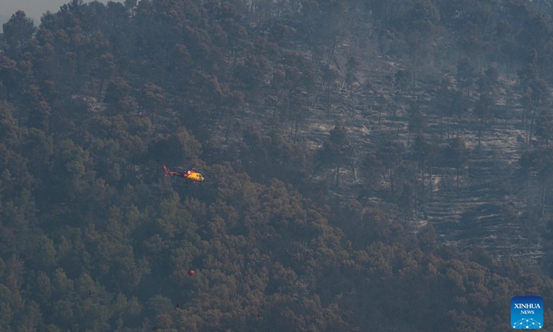 A helicopter carries water to put out a wildfire in Sentmenat, Barcelona, Spain, on July 7, 2026. According to satellite-based estimates from the European Forest Fire Information System (EFFIS), wildfires have burned around 56,000 hectares in Spain so far this year. (Photo: Xinhua)