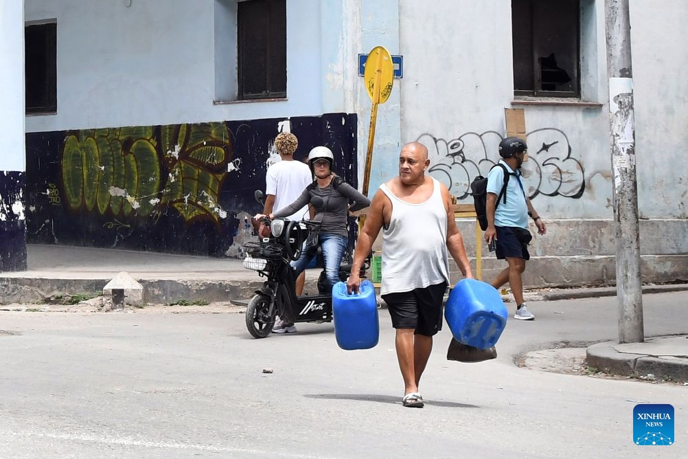 A man carrying water vessels walks along a street in Havana, capital of Cuba, on July 8, 2026. Cuban Foreign Minister Bruno Rodriguez on Tuesday accused the U.S. government of carrying out multidimensional, non-conventional warfare against Cuba, which he said has lasted for almost seven decades and become ever crueler and more ruthless during the last seven months. The cumulative damage caused by the U.S. blockade since it was first imposed amounts to 178.7 billion U.S. dollars at current prices, according to Rodriguez. (Photo: Xinhua)