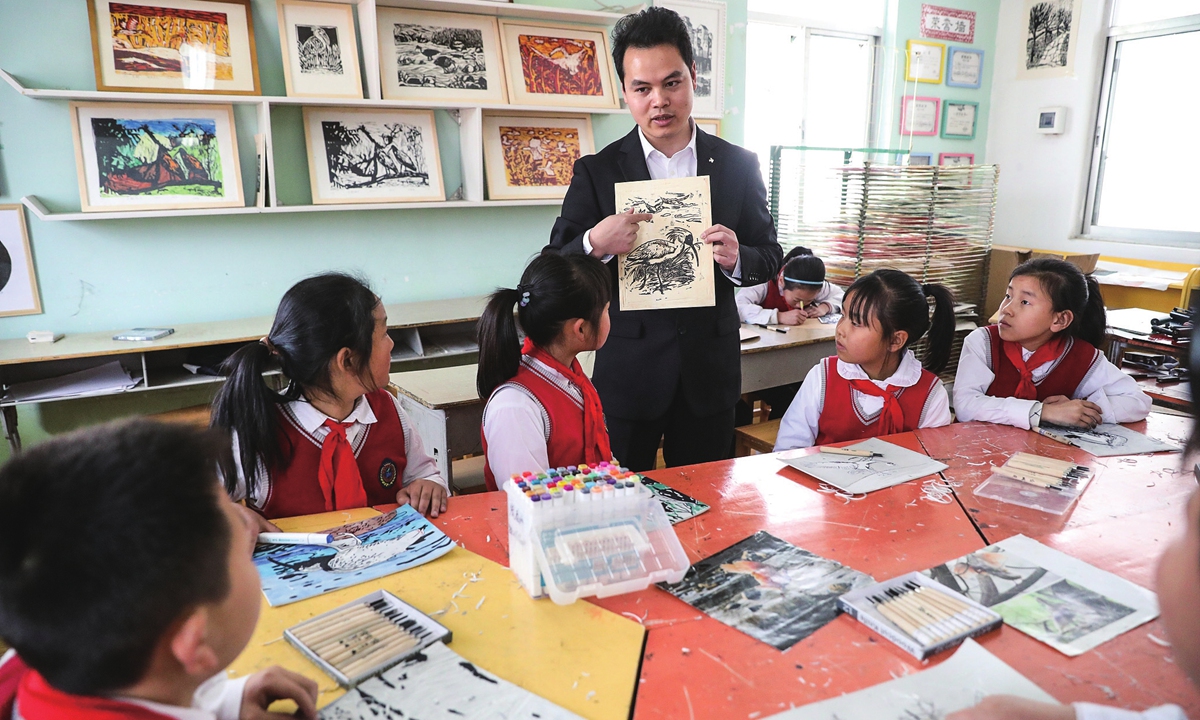 A young teacher guides students in creating woodblock prints of the crested ibis in Hanzhong, Northwest China's Shaanxi Province, on March 17, 2023.