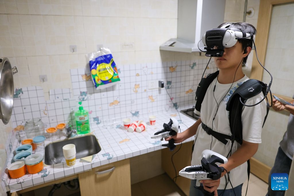 A data collector captures real-world inputs for embodied intelligent devices at a kitchen scenario in Nanming District of Guiyang City, southwest China's Guizhou Province, July 6, 2026. With the rapid development of embodied artificial intelligence (AI), a new profession, trainers of embodied AI, has emerged, which comprise roles such as data collectors. (Photo: Xinhua)