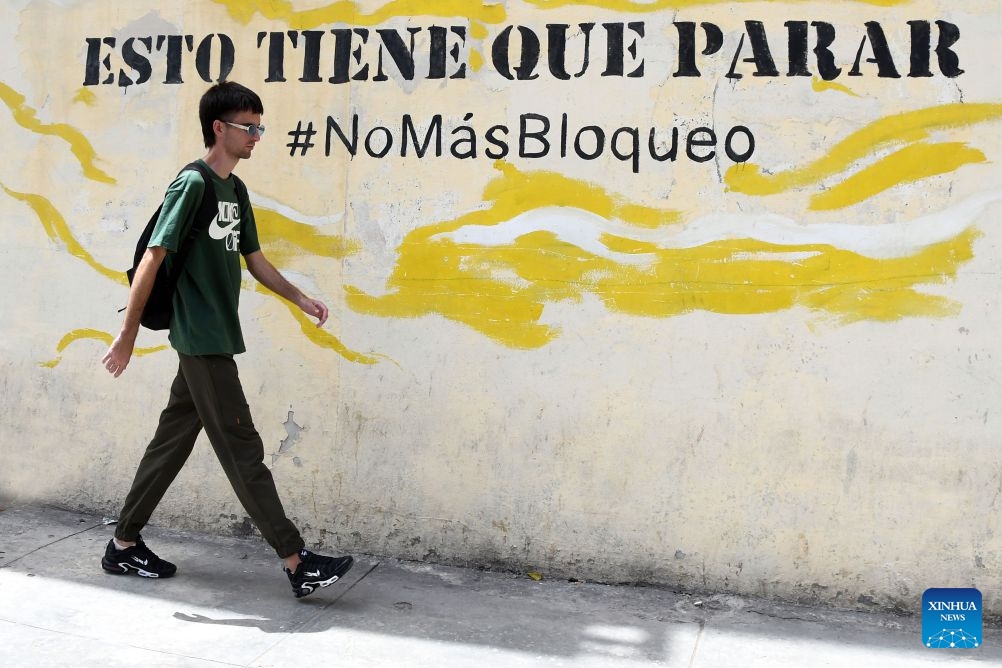 A man walks past a slogan opposing the U.S. blockade, in Havana, capital of Cuba, on July 8, 2026. Cuban Foreign Minister Bruno Rodriguez on Tuesday accused the U.S. government of carrying out multidimensional, non-conventional warfare against Cuba, which he said has lasted for almost seven decades and become ever crueler and more ruthless during the last seven months. The cumulative damage caused by the U.S. blockade since it was first imposed amounts to 178.7 billion U.S. dollars at current prices, according to Rodriguez. (Photo: Xinhua)
