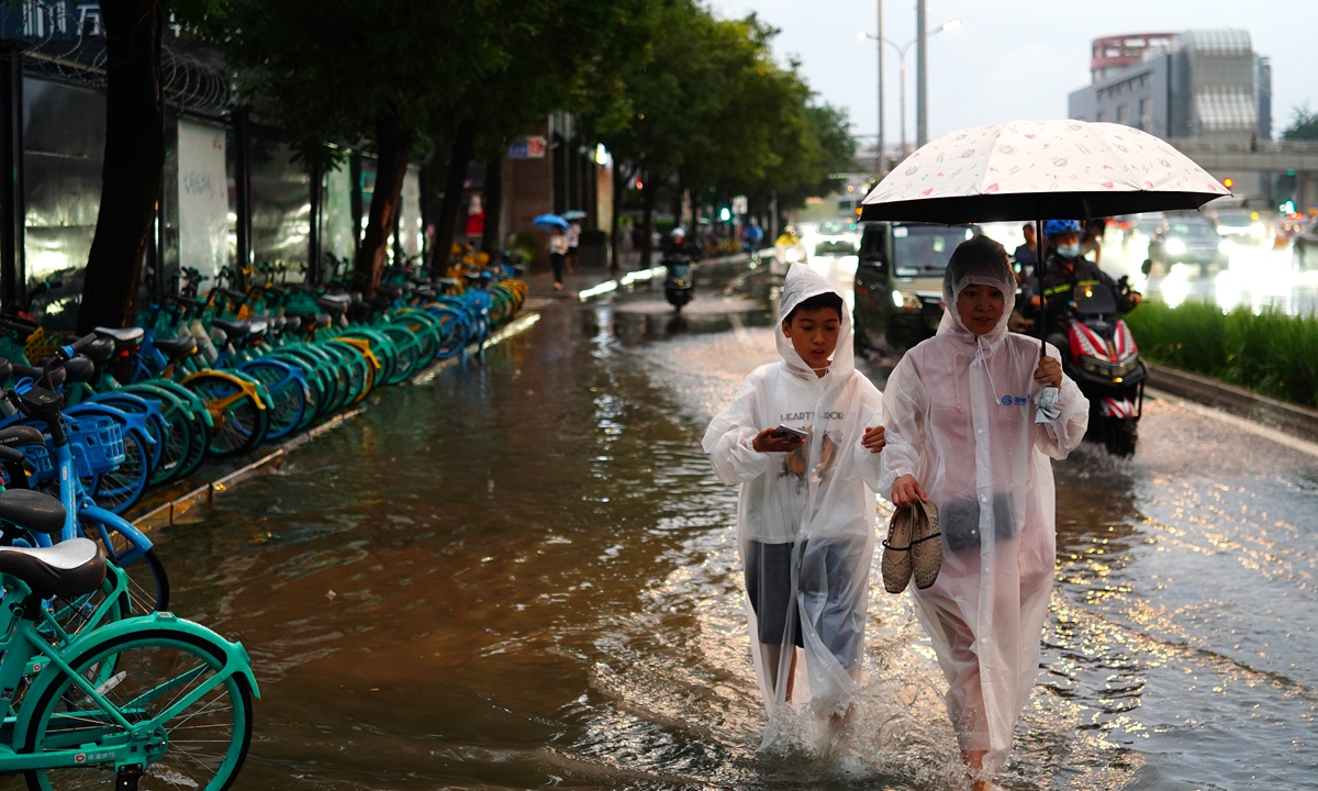 Pedestrians wade through floodwater after heavy rain lashed downtown Beijing on July 10, 2026. Photo: VCG