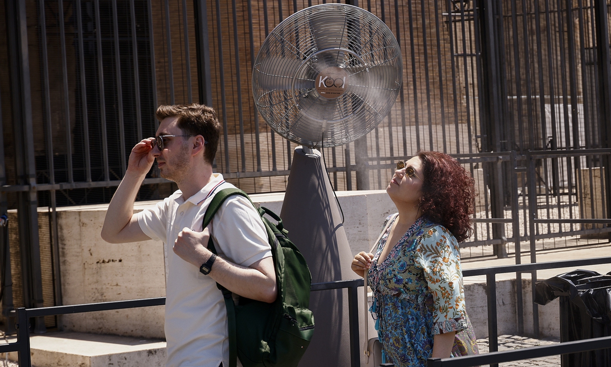 People pass by a cooling mist fan amid sweltering high temperatures in Rome, Italy, on July 1, 2026. Photo: VCG