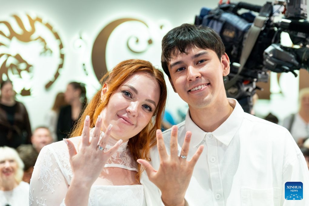 A couple display their wedding rings in Vladivostok, Russia, July 8, 2026. Vladivostok held a Wedding Festival on Wednesday, with 11 couples registering their marriages and participating in a group wedding. (Photo by Andrey Matveenko/Xinhua)