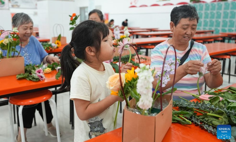 A little kid joins a flower arranging activity with family members at a temporary shelter in Miyun District in Beijing, capital of China, July 11, 2026.

