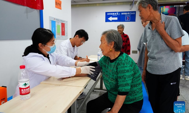 A medical worker measures the blood pressure of an elderly resident at a temporary shelter in Pinggu District in Beijing, capital of China, July 11, 2026.

