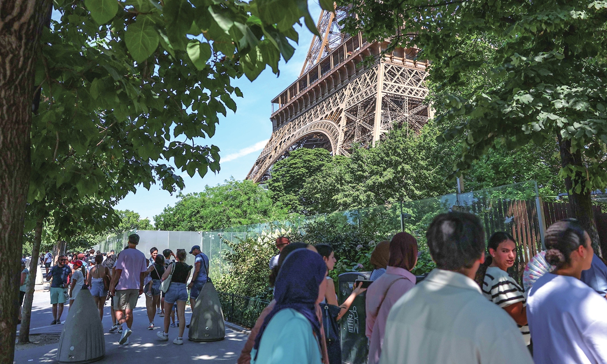 Tourists seek some shade near the Eiffel Tower as the landmark closed early due to soaring temperatures amid a heatwave in Paris, France, on July 11, 2026. The Eiffel Tower announced on Saturday that it would close at 4 pm on Saturday and Sunday, media reported. Photo: VCG