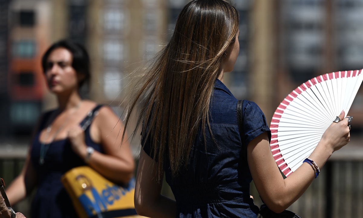 People try to cope with the scorching heat by drinking plenty of water, using umbrellas and handheld fans as a new heatwave is expected to push temperatures above 30 degrees Celsius, in London, United Kingdom, on July 8, 2026. Photo: VCG