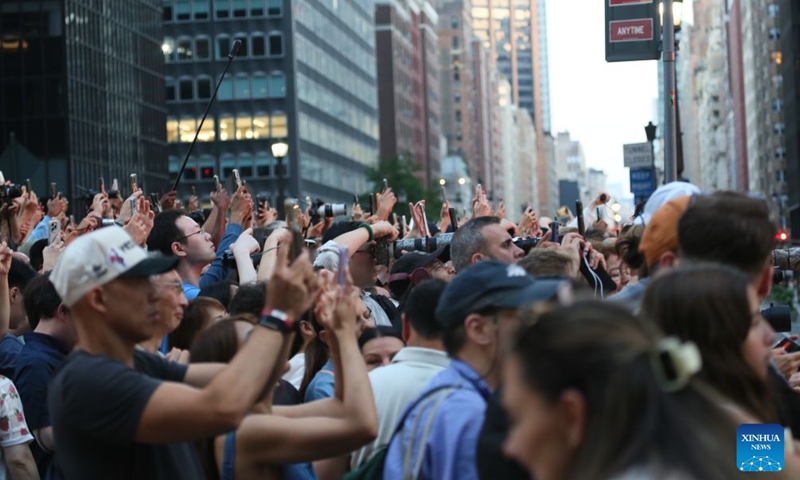 People take photos of the Manhattanhenge in Manhattan of New York, the United States, on July 12, 2026. The Manhattanhenge refers to the twice-a-year circumstance during which the setting sun aligns precisely with the east-west streets of Manhattan. (Xinhua/Zhang Fengguo)