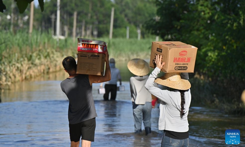 People wade through floodwaters to deliver emergency supplies in Shishe Village in Guigang, south China's Guangxi Zhuang Autonomous Region, July 10, 2026.

