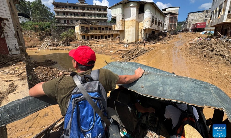 Li Henghao (1st L) and Su Derong (1st R) are seen on a vehicle after the main road leading to Zhenlong Township was preliminarily opened to traffic in Zhenlong Township, Hengzhou City, Nanning, south China's Guangxi Zhuang Autonomous Region, July 11, 2026.