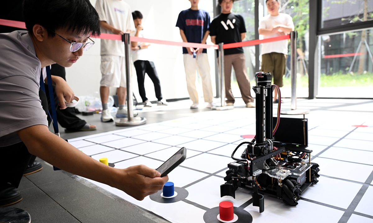 A participant calibrates a robot during an artificial intelligence and industrial robot competition between teams from the Chinese mainland and the Taiwan island at Fuzhou University in East China's Fujian Province on July 13, 2026. The event featured four categories - intelligent material-handling robots, unmanned vehicle obstacle avoidance, a creative competition, and a cross-Straits integrated creative application contest. Photo: CNS Photo