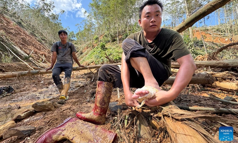 Li Henghao (R) wraps his chafed foot with gauze in Zhenlong Township, Hengzhou City, Nanning, south China's Guangxi Zhuang Autonomous Region, July 10, 2026.