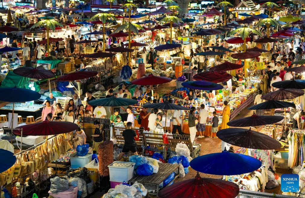 This photo taken on July 14, 2026 shows a view of the Starlight Night Market in Jinghong, Xishuangbanna Dai Autonomous Prefecture, southwest China's Yunnan Province. The Starlight Night Market, located in Jinghong of Xishuangbanna Dai Autonomous Prefecture, has witnessed a surge in visitor arrivals during the summer peak tourism season. Featuring local delicacies, ethnic culture and diverse nighttime consumption options, this night market reflects the vitality of local cultural and tourism market. (Photo: Xinhua)