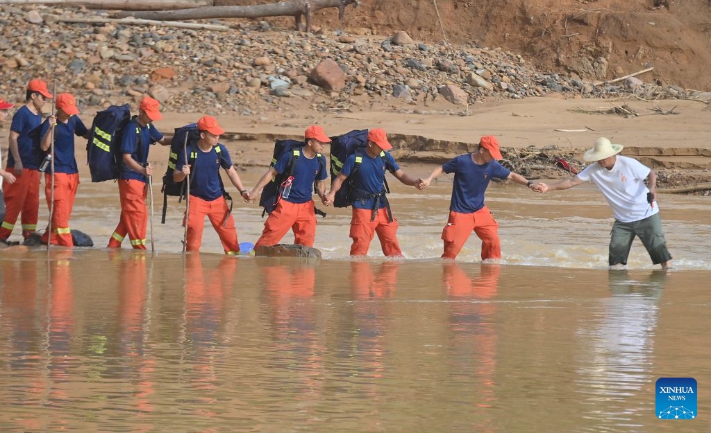 Rescuers wade through water hand in hand to transport relief supplies in Zhenlong Township, Hengzhou City, south China's Guangxi Zhuang Autonomous Region, July 11, 2026. Efforts are underway to support flood relief and recovery in Guangxi, which has been hit by severe rainstorms and flooding caused by Typhoon Maysak. (Photo: Xinhua)