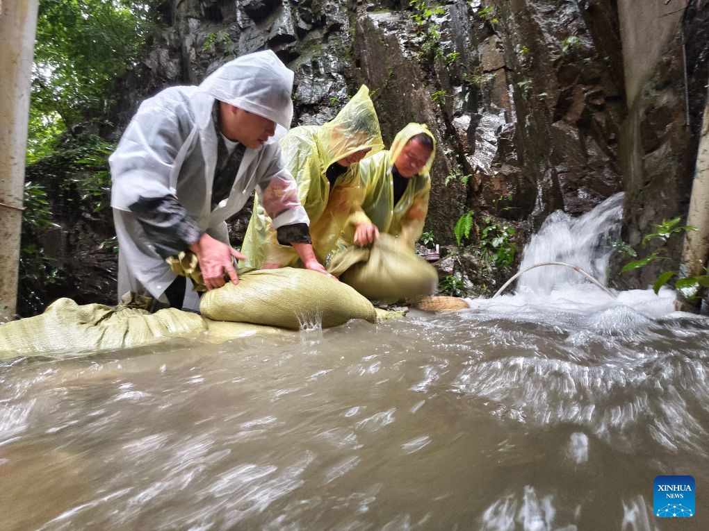 This photo taken by a mobile phone shows party members and officials placing sandbags to hold back floodwaters at Gaoling Village of Lin'an District in Hangzhou, east China's Zhejiang Province, July 12, 2026. As extreme weather has battered multiple regions across China in recent days, local authorities have implemented disaster prevention and relief measures to safeguard people's lives and property. (Photo: Xinhua)