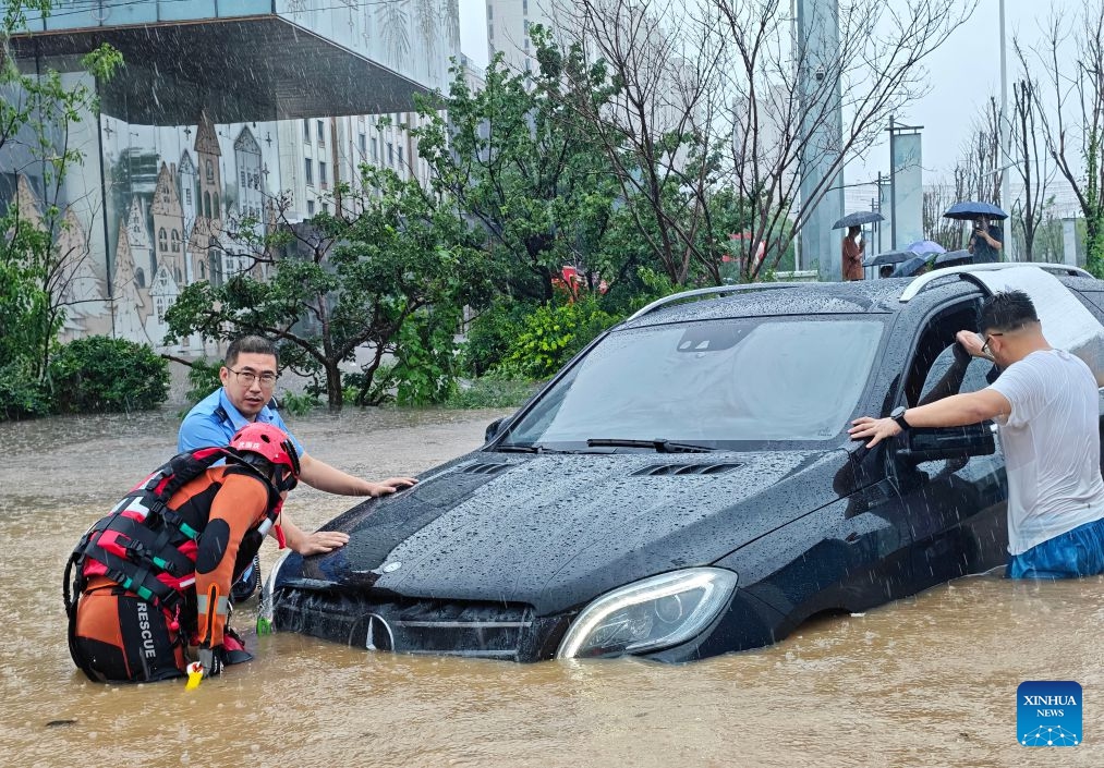 A police officer and firefighter help rescue a stranded car amid rain in Shenyang, northeast China's Liaoning Province, on July 13, 2026. From Sunday to Monday, heavy to torrential rain lashed central Liaoning Province. Several cities, including Shenyang and Fushun, suspended classes, business operations and work on Monday as a precaution, while water levels in several rivers rose significantly due to the heavy rainfall. (Photo: Xinhua)