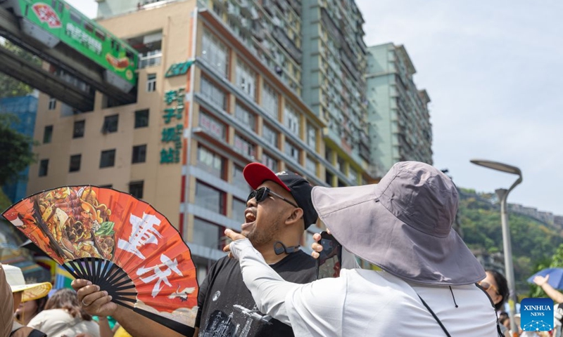 A foreign tourist poses for photos with his mouth open, pretending to swallow a monorail as it passes through a residential building, at Liziba lookout in Yuzhong District of southwest China's Chongqing Municipality, April 23, 2026. Since the beginning of this year, inbound and outbound passenger traffic at Chongqing Jiangbei International Airport has continued to grow, with a significant increase in foreign passenger traffic. In the first half of 2026, the airport handled more than 1.48 million inbound and outbound passenger trips, up 39.5 percent year on year. (Photo: Xinhua)