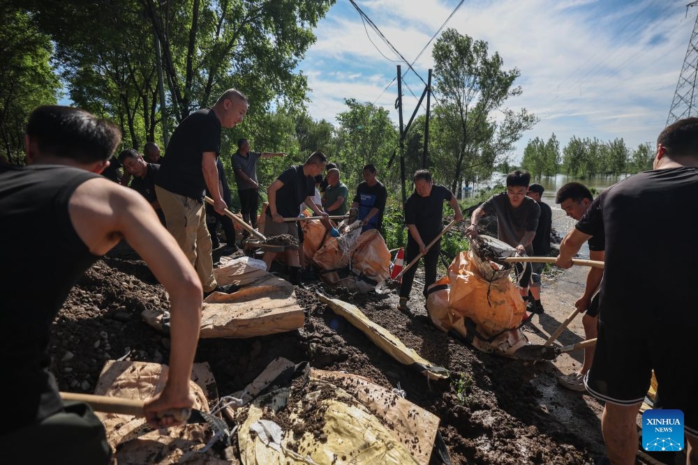 Emergency workers fill sandbags at a dike at Yujiatai Village of Liaozhong District, Shenyang, northeast China's Liaoning Province, July 14, 2026. Emergency responding workers in riverside towns and villages of Liaozhong District of Shenyang are working to heighten and fortify the dikes as upstream flood discharge continues to rise the water level in the river. (Photo: Xinhua)