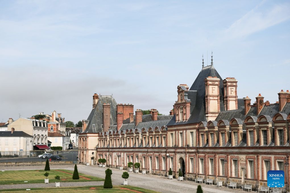 This photo taken on July 14, 2026 shows the Palace of Fontainebleau in Seine-et-Marne, France, with smoke from a wildfire rising in the distance. French police have detained 59 people across the country in connection with wildfires, including two suspects linked to the blaze in the Fontainebleau forest in Seine-et-Marne department, southeast of Paris, French Interior Minister Laurent Nunez said on Monday. (Photo: Xinhua)