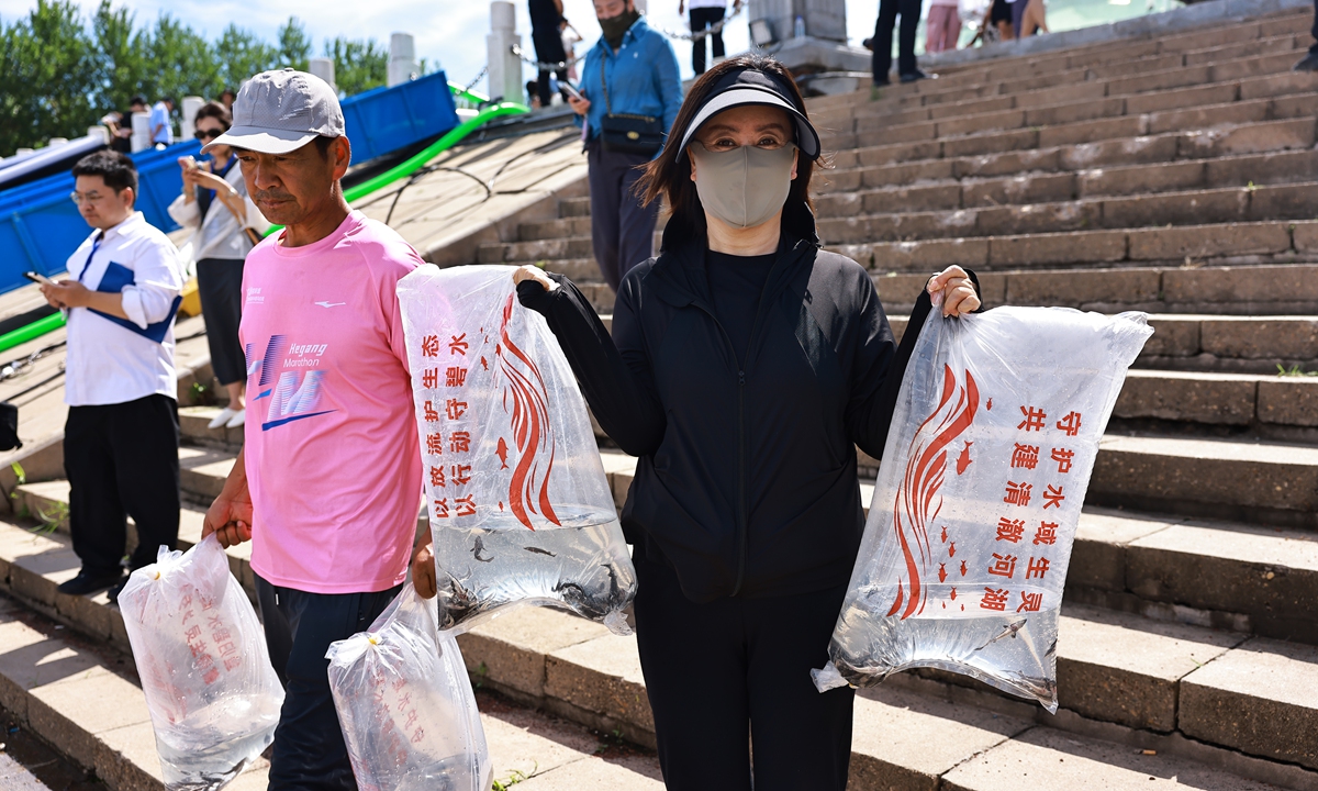 A Tongjiang local resident poses for a picture with two bags of fry to be released in the joint fish stock enhancement and release activity in Tongjiang, Jiamusi, Northwest China's Heilongjiang Province on July 14, 2026. Photo: Deng Xiaoci/GT