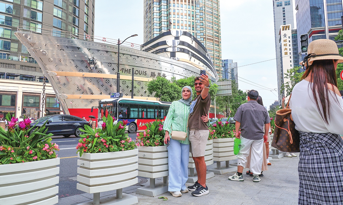 Foreign tourists take selfies at a scenic spot in Shanghai on July 14, 2026. Following the passage of Typhoon Bavi, Shanghai activated an orange heat alert as temperatures soared above 37 C, yet tourists carried on sightseeing despite in the scorching heat. Photo: VCG