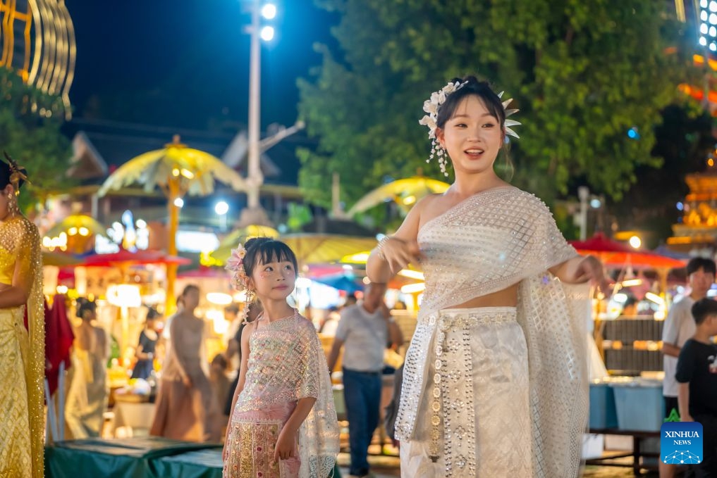 Tourists in ethnic attire are seen at the Starlight Night Market in Jinghong, Xishuangbanna Dai Autonomous Prefecture, southwest China's Yunnan Province, July 14, 2026. The Starlight Night Market, located in Jinghong of Xishuangbanna Dai Autonomous Prefecture, has witnessed a surge in visitor arrivals during the summer peak tourism season. Featuring local delicacies, ethnic culture and diverse nighttime consumption options, this night market reflects the vitality of local cultural and tourism market. (Photo: Xinhua)