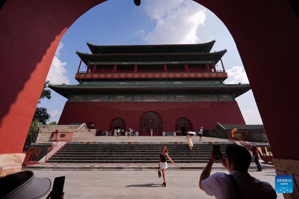 A visitor poses for photos at the Drum Tower in Beijing, capital of China, July 27, 2026. 