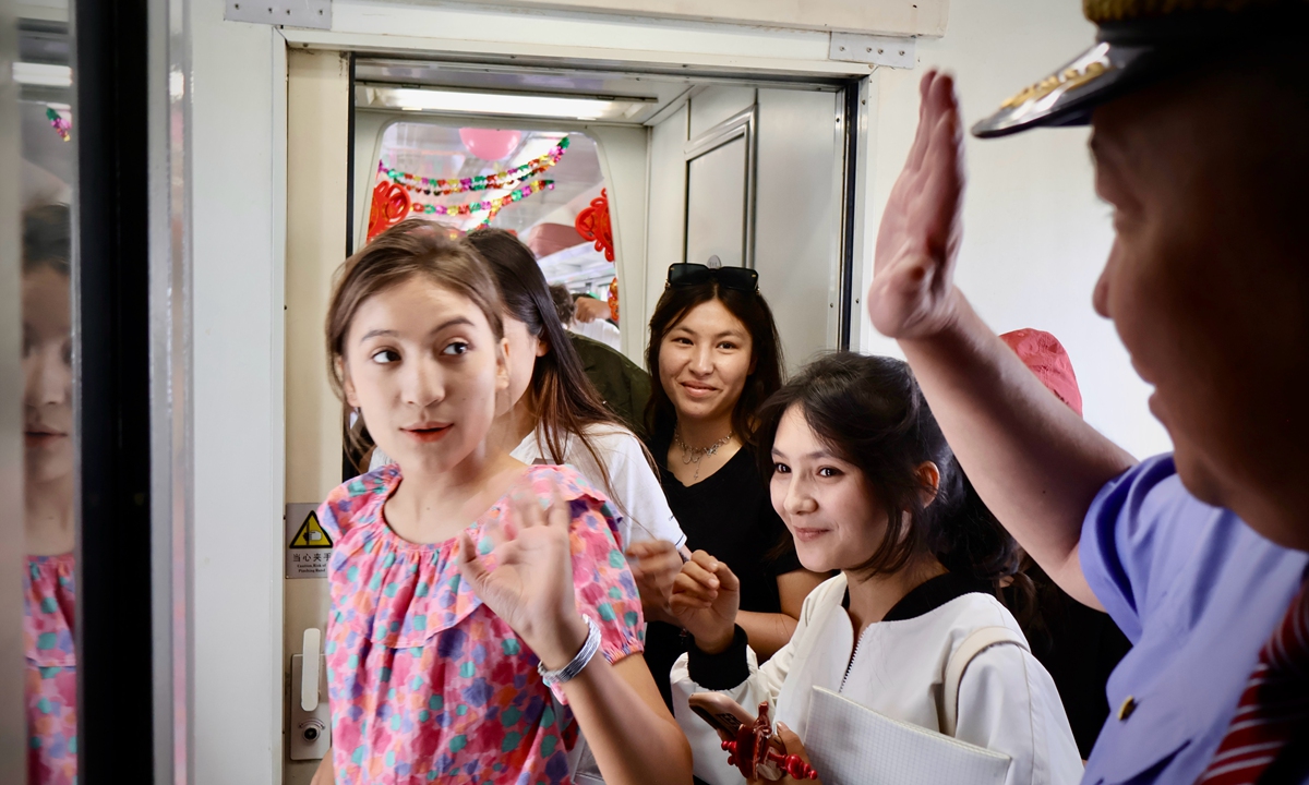 Passengers aboard Train 7558 wave goodbye to Polatkhan, the chief conductor, before alighting on June 25, 2026. Photo: Lin Xiaoyi/GT