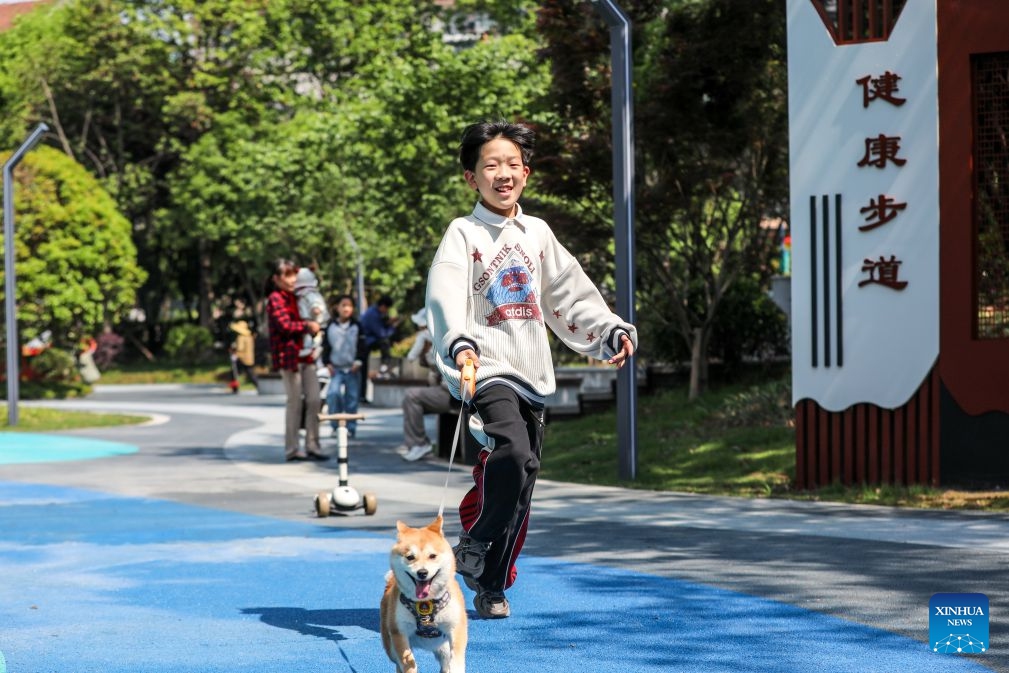 A child walks a dog at a pocket park in Deqing County of Huzhou City, east China's Zhejiang Province, April 30, 2026. During China's 14th Five-Year Plan period (2021-2025), over 240,000 old urban residential compounds were renovated across the country, benefiting more than 40 million households and 110 million residents. (Photo: Xinhua)