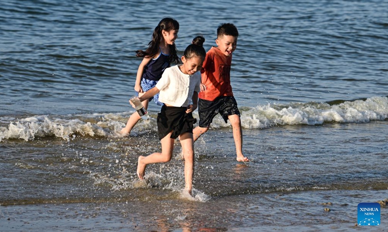 People have fun along the seashore in Tanmen Town, Qionghai, south China's Hainan Province, July 24, 2026. 