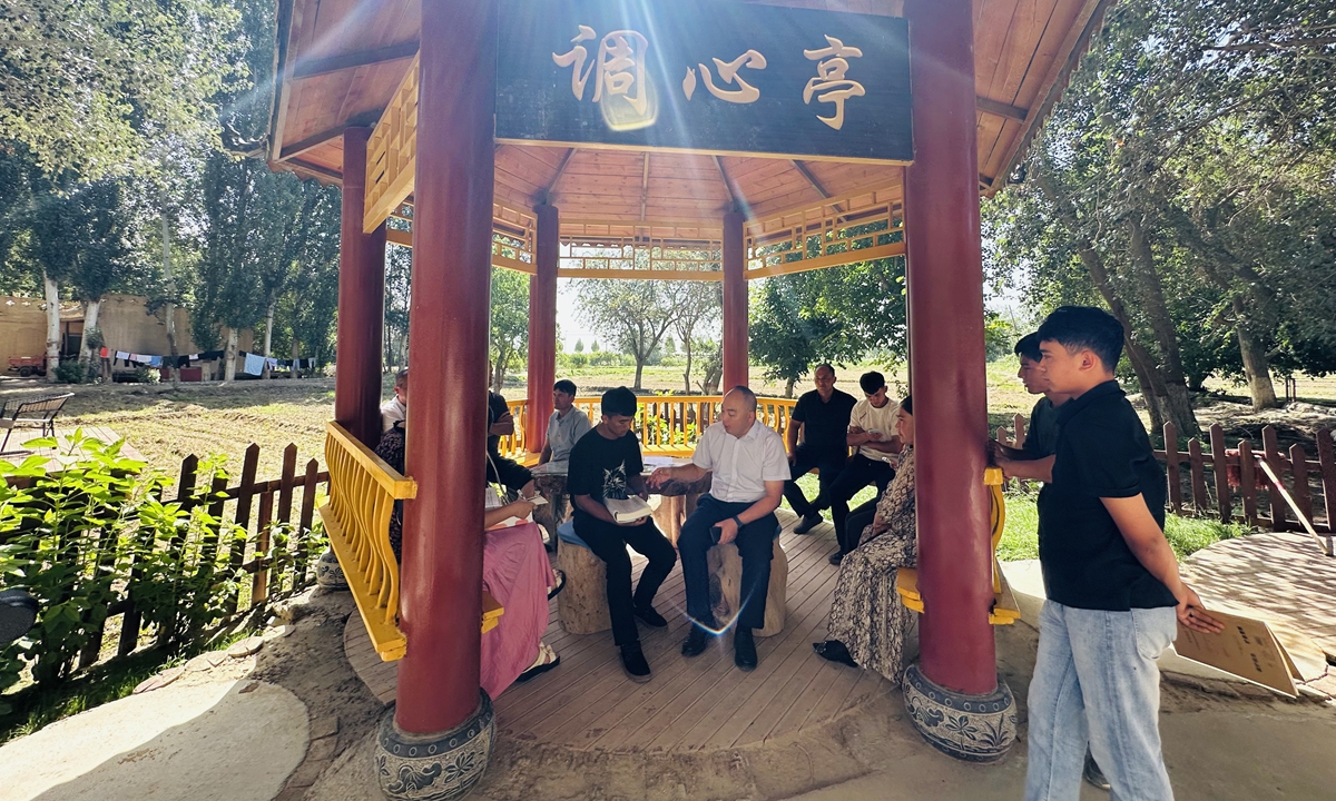 Villagers gather around township officials and counselors to discuss college application strategies for local students at the Heart-Calming Courtyard in Daoxiang Village, Hotan County, on June 26, 2026. Photo: Lin Xiaoyi/GT