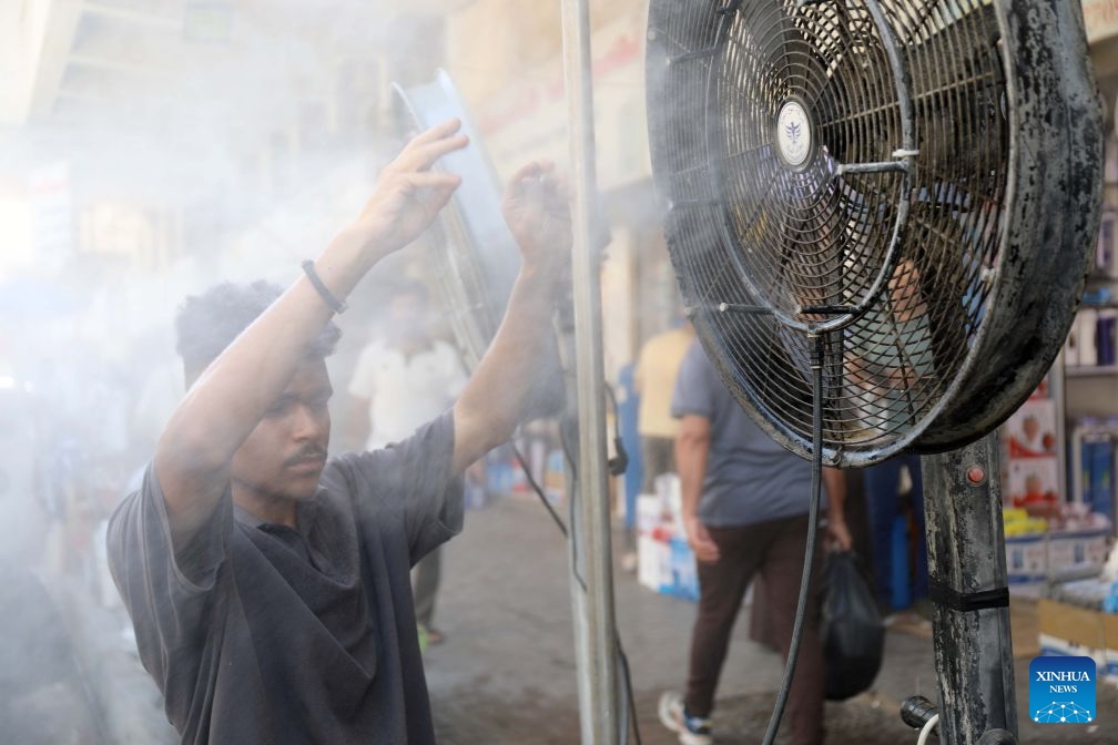 A man cools off in front of a water-misting fan on a street in Baghdad, Iraq, July 16, 2026. (Xinhua/Khalil Dawood)