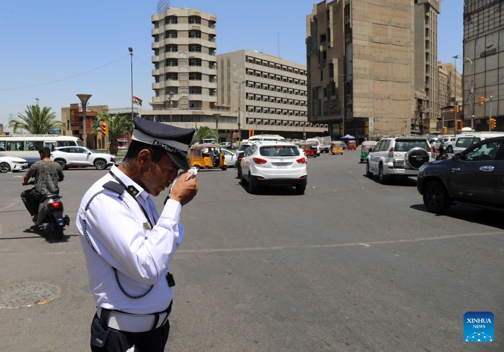 A traffic policeman wipes sweat from his face under the scorching sun in Baghdad, Iraq, July 16, 2026. (Xinhua/Khalil Dawood)