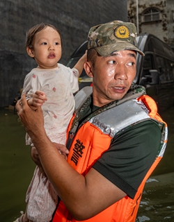 An armed police officer evacuates a child stranded by flooding in Guigang, Guangxi, on July 8, 2026. Photo: IC